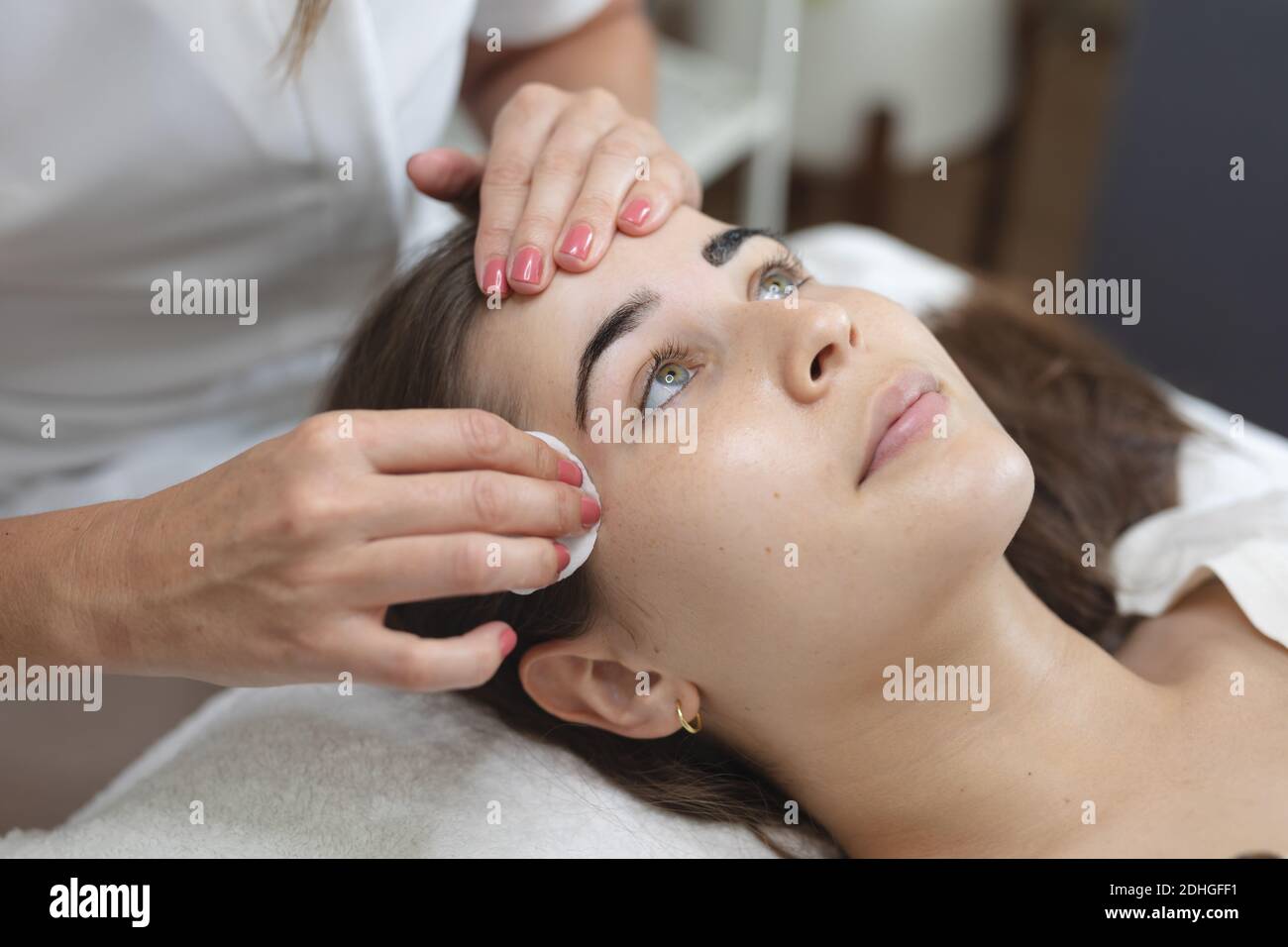 Donna caucasica sdraiata indietro mentre beautician le asciuga le sopracciglia Foto Stock