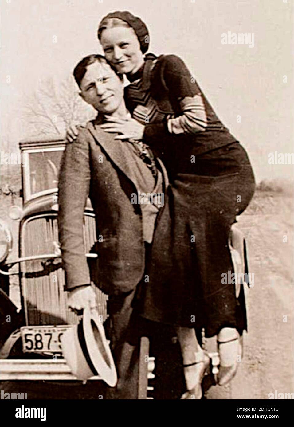 Bonnie Parker e Clyde Barrow, tra il 1932 e il 1934, quando le loro imprese in Arkansas includevano omicidio, rapina e rapimento. Contrariamente alla credenza popolare, i due non si sposarono mai. Erano in un rapporto di lunga data. In posa davanti a una Ford V8 1932. Foto Stock