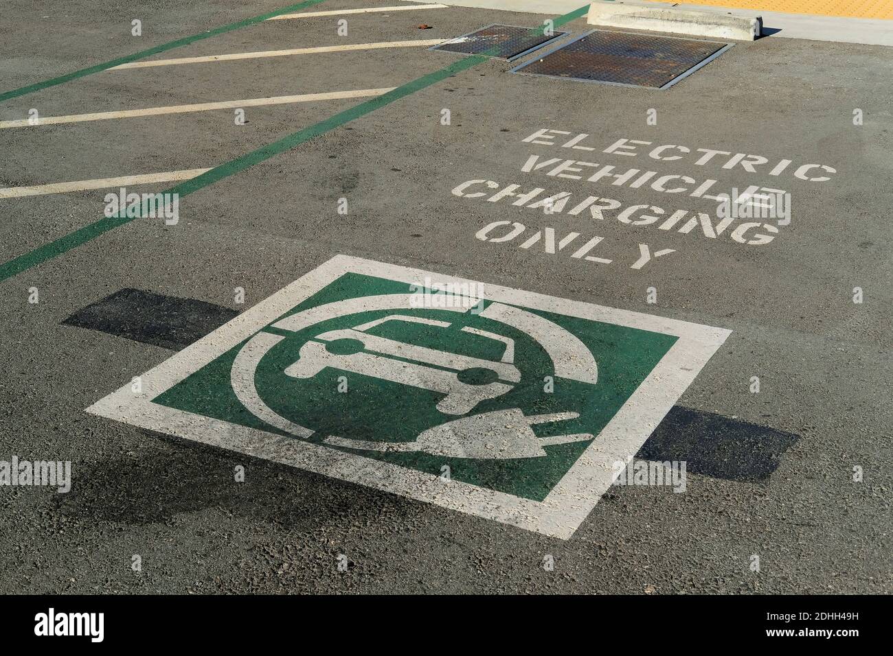 Ricarica del veicolo elettrico solo in lettere bianche stencilate sul pavimento di un'area di ricarica EV in un parcheggio; simbolo grafico di ricarica EV. Foto Stock