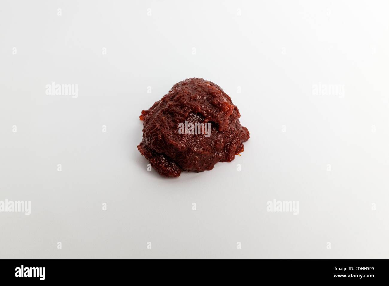 Pasta di pepe rosso e piccante su fondo bianco Foto Stock