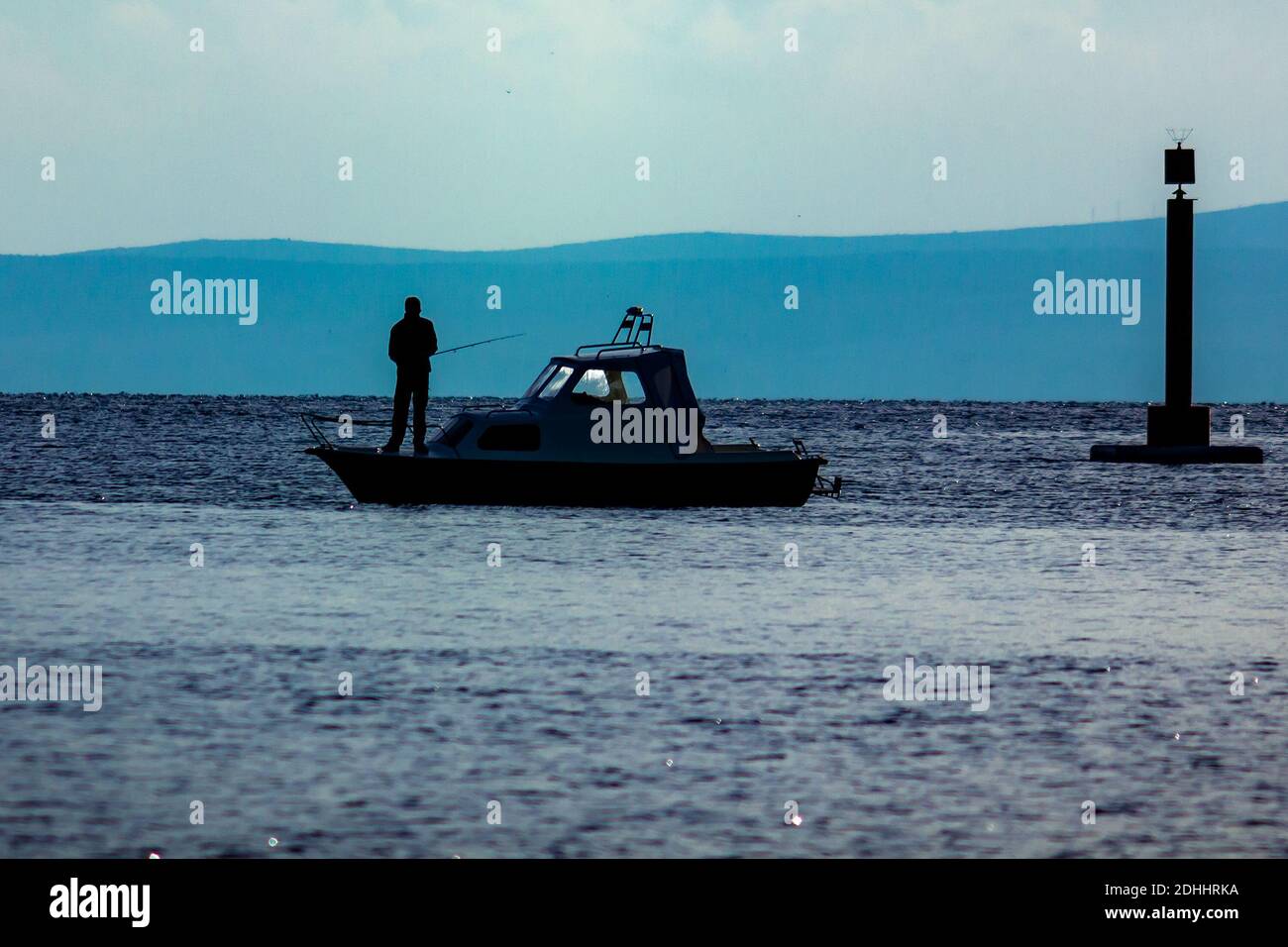 Un bel colpo di una silhouette di un pescatore dentro una barca Foto Stock