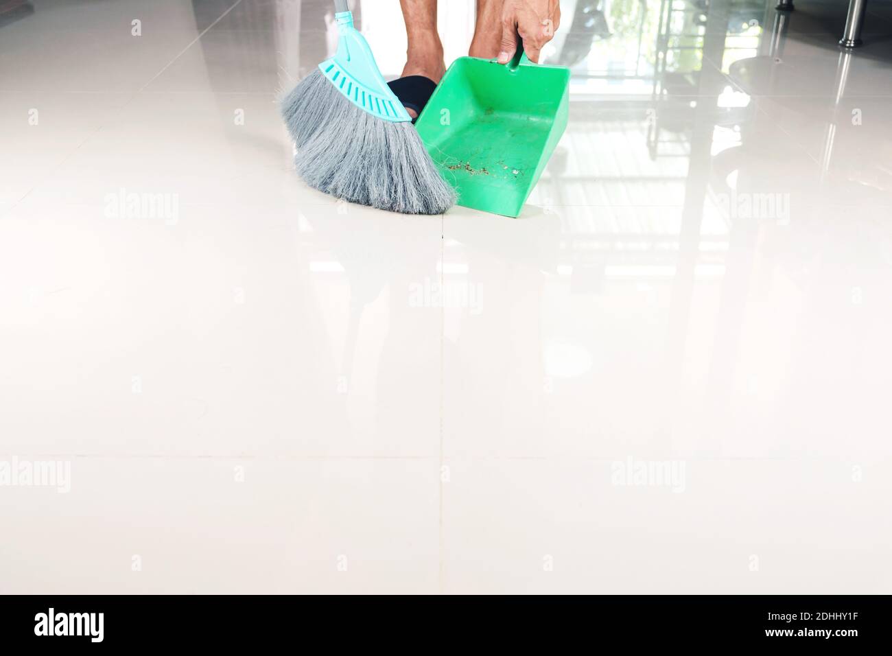 Pulire i pavimenti piastrellati con una scopa di plastica e un cassettiera per la polvere. Foto Stock