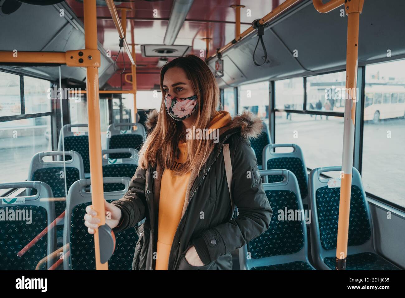 donna con maschera facciale covid-19 mezzi pubblici, fermata dell'autobus Foto Stock