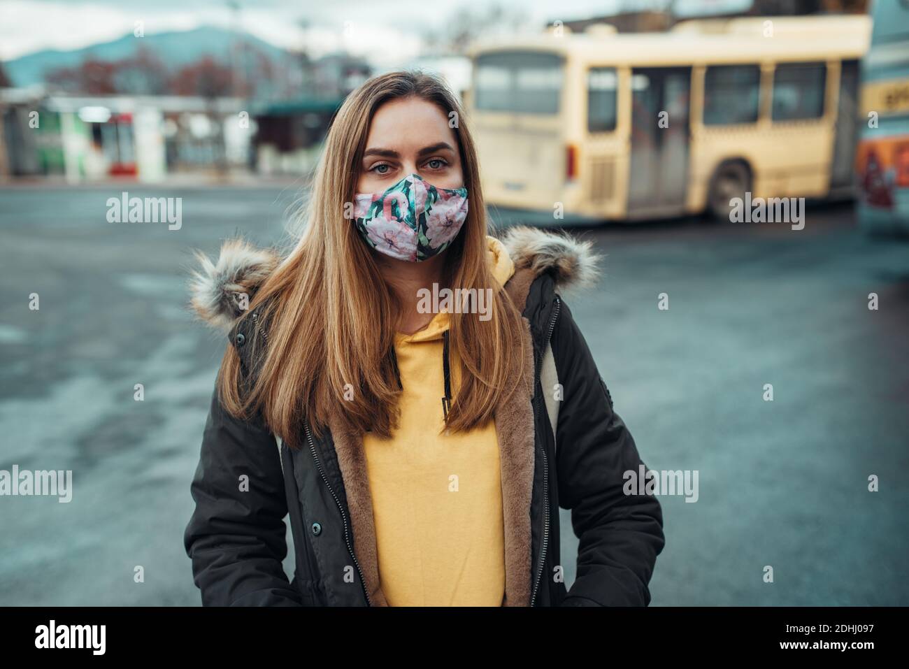 donna con maschera facciale covid-19 mezzi pubblici, fermata dell'autobus Foto Stock