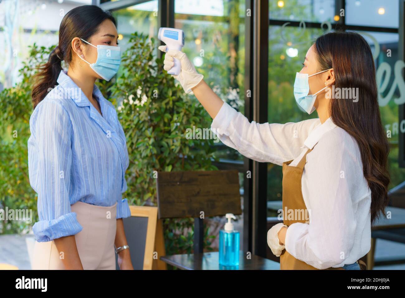 Donna asiatica impiegato caffè prendere temperatura asiatica donna con faccia maschera prima di andare al ristorante o caffè per nuovo stile di vita normale coronavirus cov Foto Stock