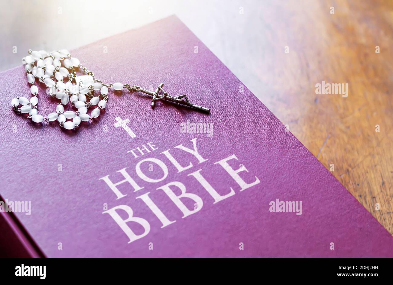 Un rosario di perline bianche con un crocifisso d'argento sopra la copertina del libro sacro chiuso della bibbia. Religione e speranza. Oggetti religiosi per pregare Foto Stock