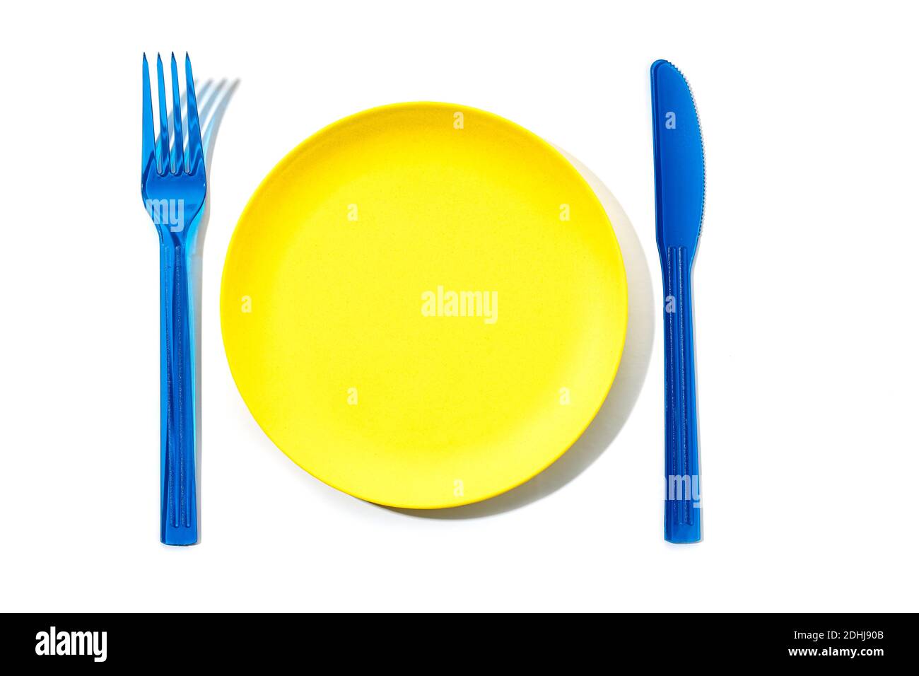 Piastra vuota in plastica colorata, forcella e coltello isolati su sfondo bianco. Vista dall'alto Foto Stock