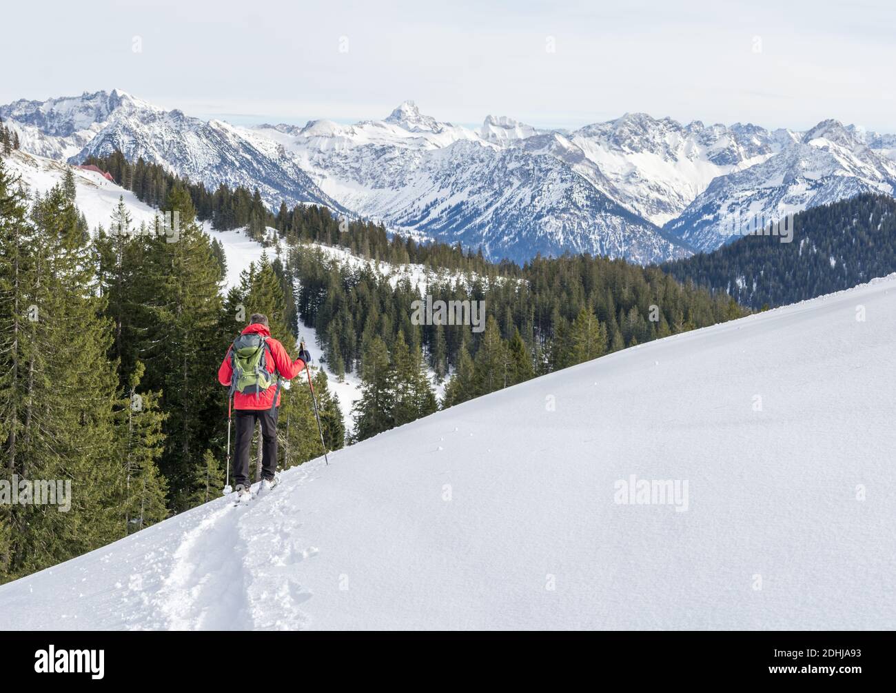 L'uomo anziano è l'escursionismo con racchette da neve nelle montagne alpine innevate. Allgau, Baviera, Germania. Foto Stock
