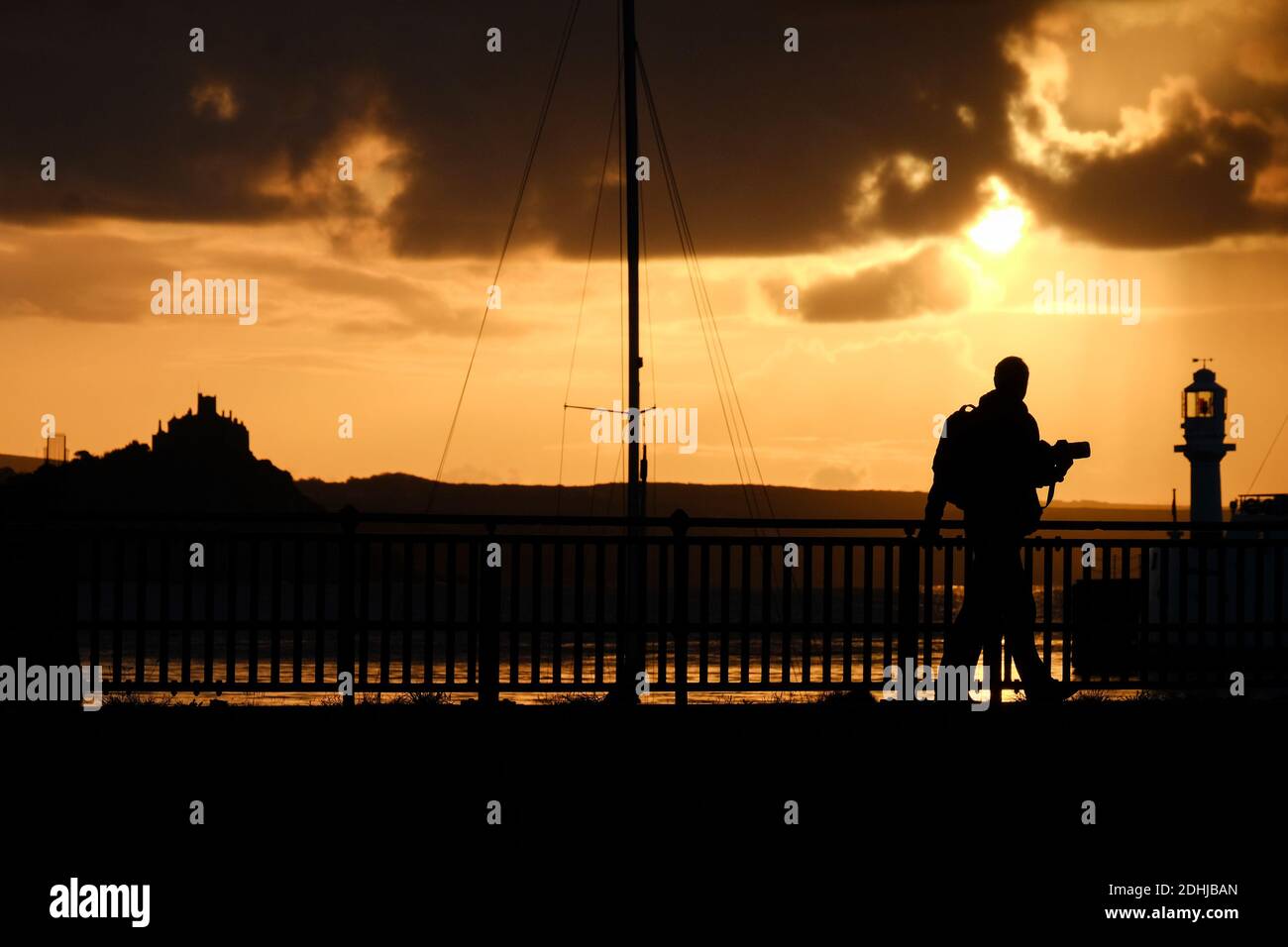Un fotografo cattura la calma prima di Storm Alex, mentre il sole sorge dietro il faro del porto di Penzance il primo giorno di ottobre. Foto Stock