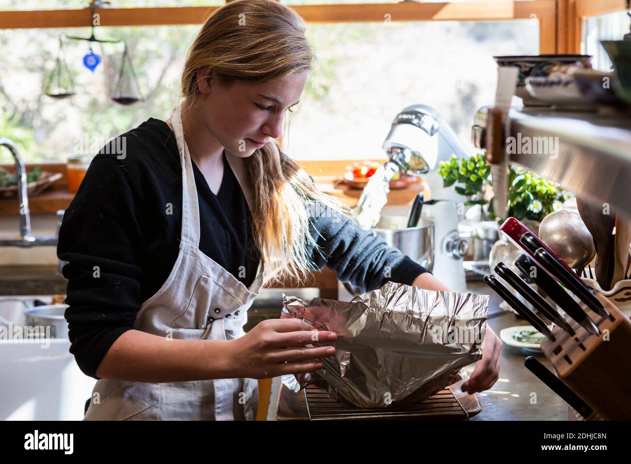 ragazza adolescente in cucina che cotta una torta. Foto Stock