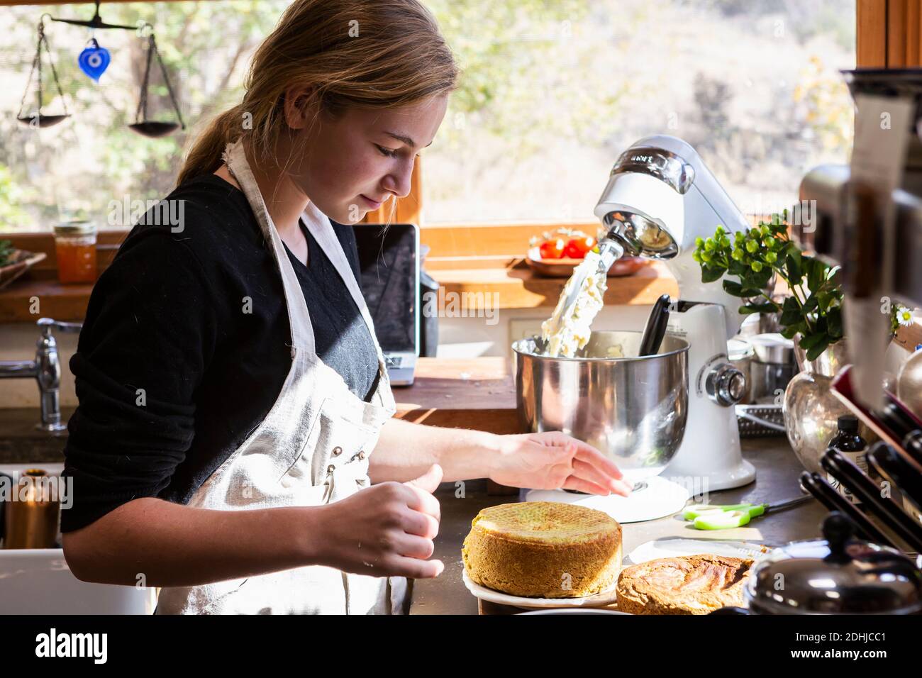 ragazza adolescente in cucina che cotta una torta. Foto Stock