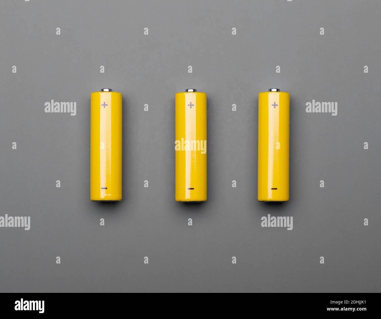 Tre batterie alcaline AA gialle o celle ricaricabili grigie sfondo colori trendy del concetto tonato anno 2021 Foto Stock
