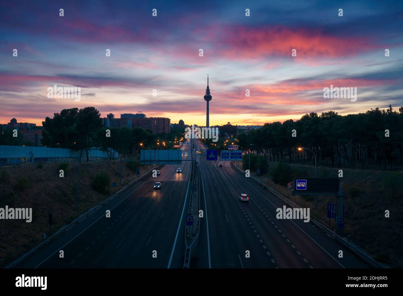 Scenario di una strada senza fine con auto in auto sotto il colorato tramonto Cielo a Madrid Foto Stock