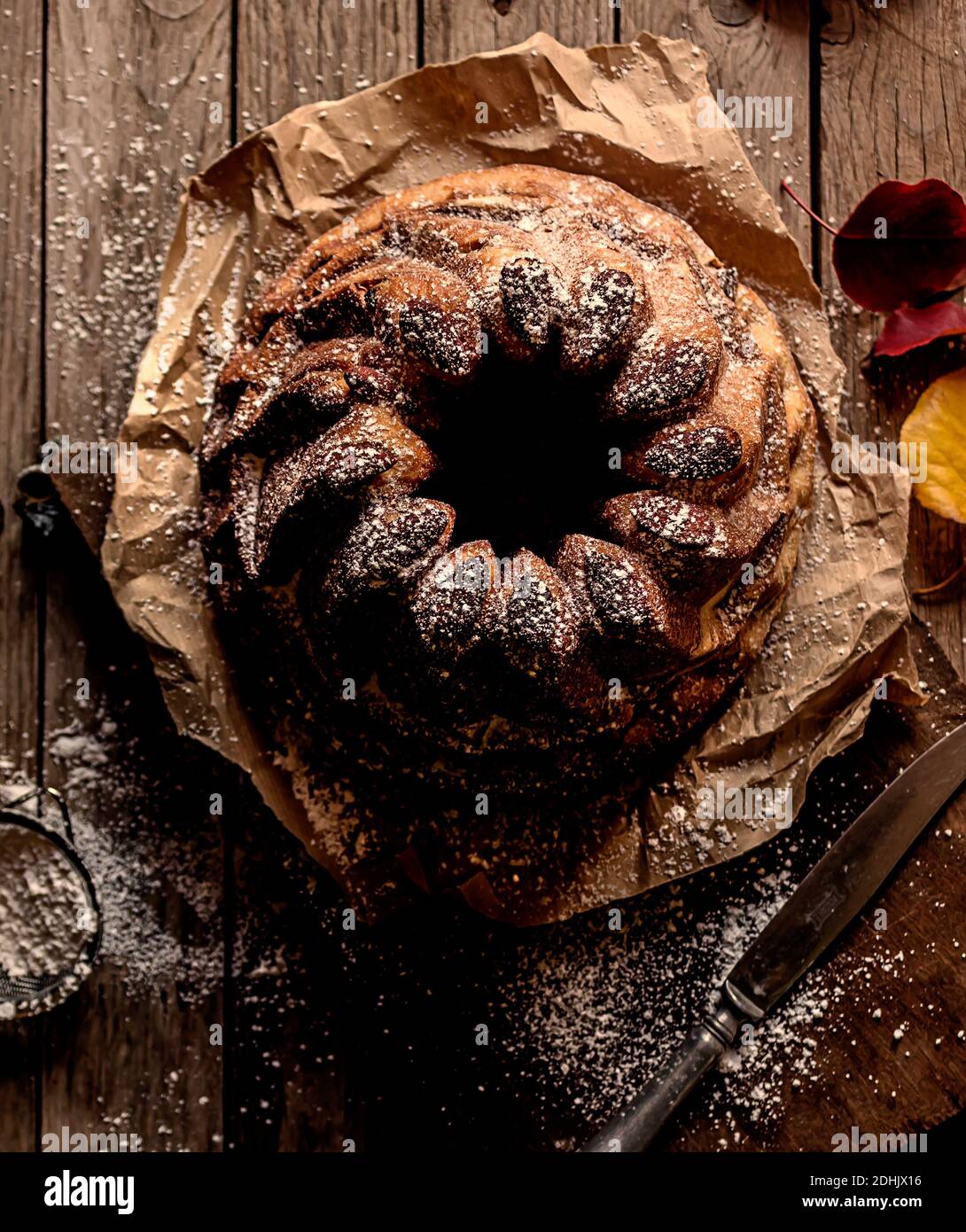Dall'alto fresco gustoso Kugelhopf sul tavolo di legno stagionato vicino foglie di autunno asciutte Foto Stock