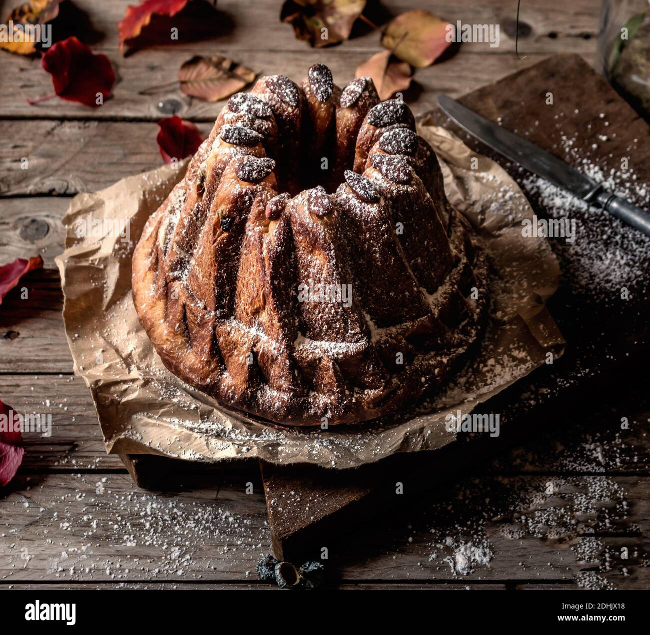 Dall'alto fresco gustoso Kugelhopf sul tavolo di legno stagionato vicino foglie di autunno asciutte Foto Stock