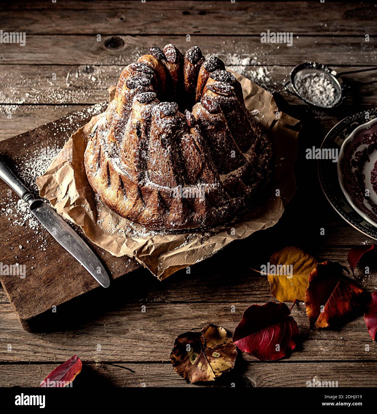 Dall'alto fresco gustoso Kugelhopf sul tavolo di legno stagionato vicino foglie di autunno asciutte Foto Stock