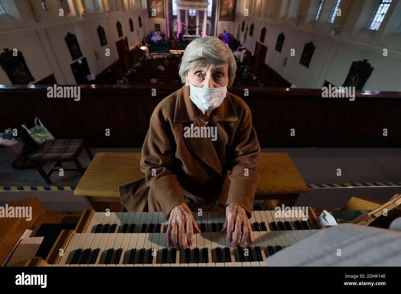 Margaret McCrisken, il giocatore di organi della chiesa di St. Mary nella città di Belfast per cinquant'anni, si prepara a giocare durante la messa, poiché le restrizioni nell'Irlanda del Nord vengono revocate in seguito a un blocco di due settimane di interruzione del circuito volto a arginare la diffusione del coronavirus. Foto Stock