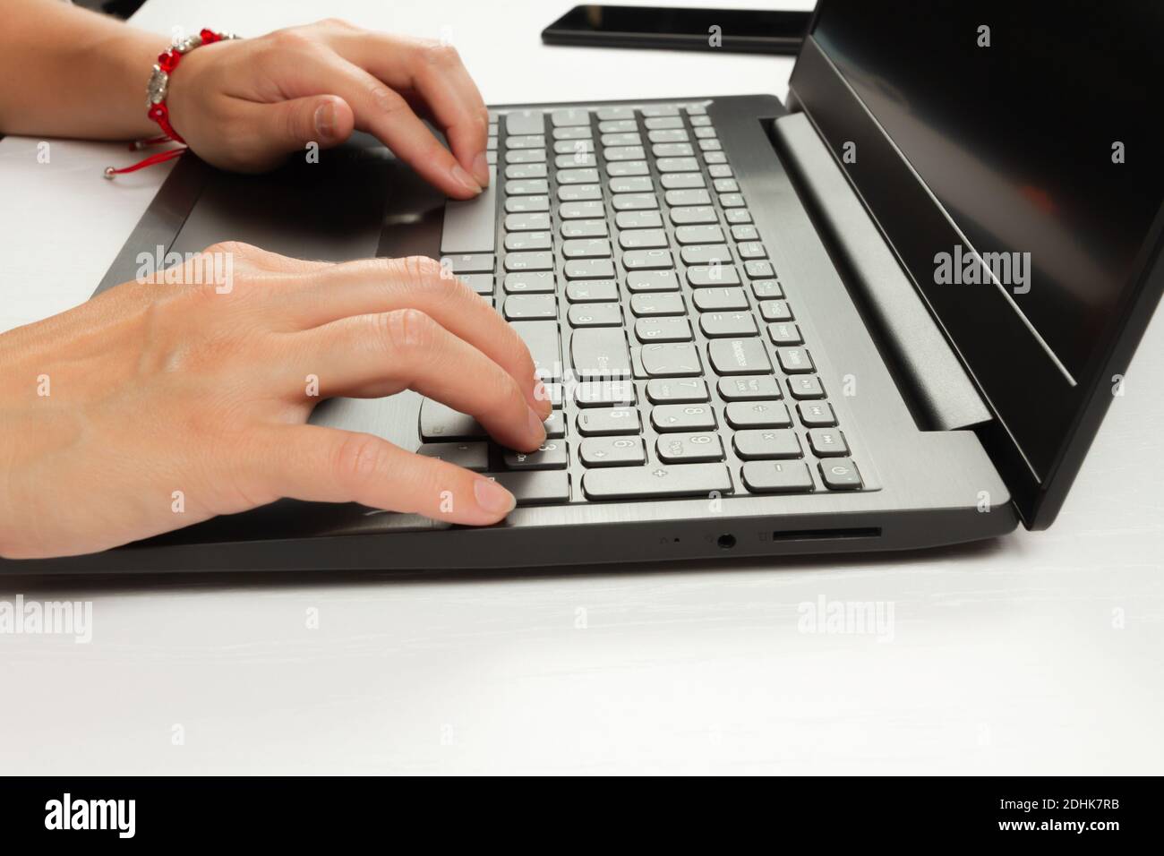 le mani femminili stanno digitando il testo sulla tastiera del portatile su bianco tavolo di legno sfondo Foto Stock