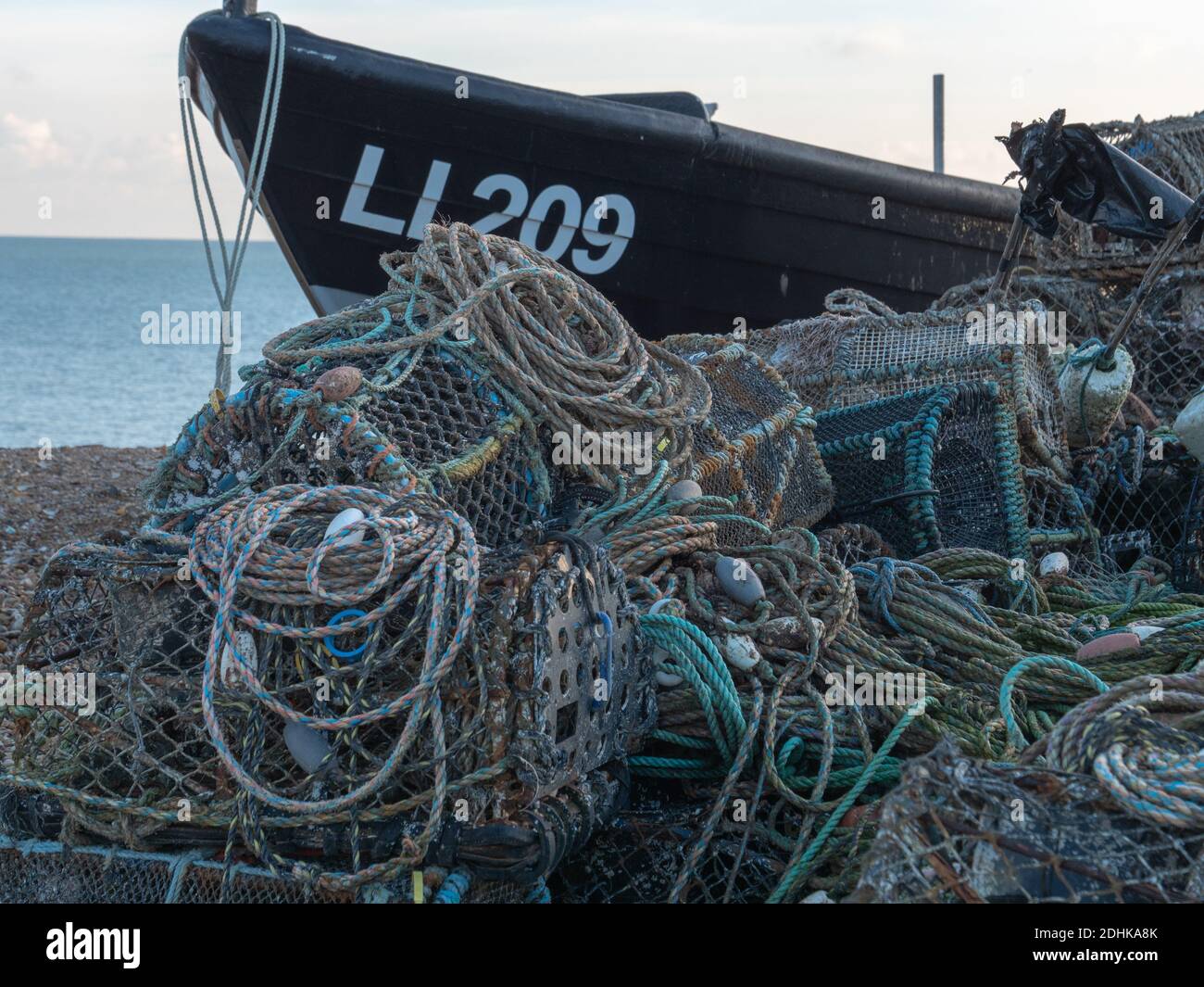 Le trappole e le pentole dell'aragosta sono viste sulla riva con una piccola barca da pesca sulla costa di Bognor Regis, West Sussex, Inghilterra, Regno Unito Foto Stock
