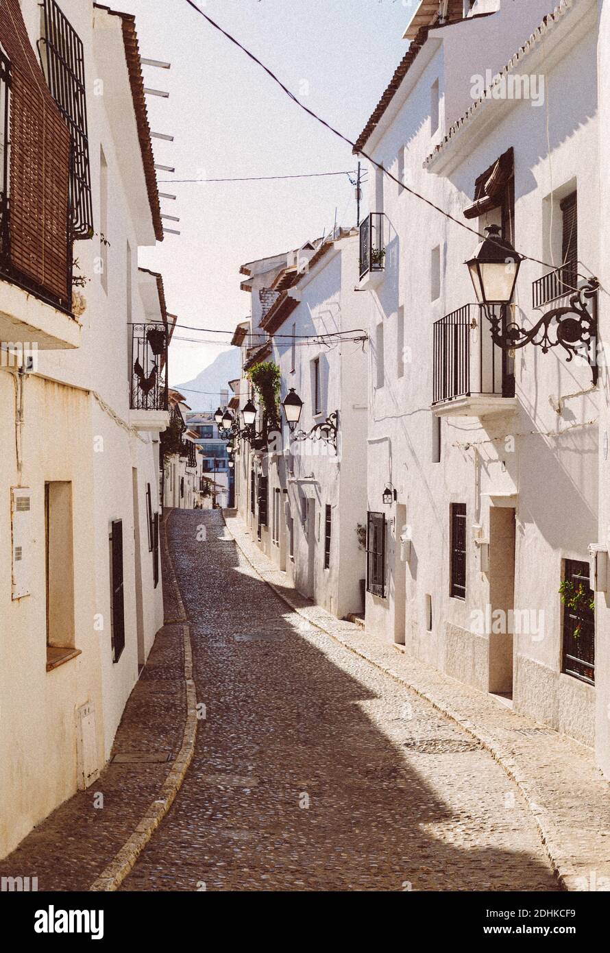 ALTEA, SPAGNA - Set 20, 2020: Affascinanti edifici bianchi tradizionali su una strada nella città di Altea con rocce asfalto. Foto Stock