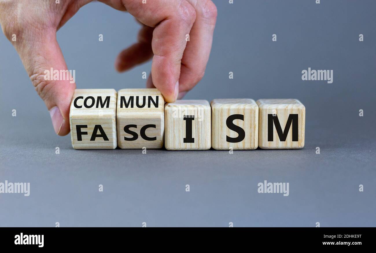 Simbolo del comunismo o del fascismo. La mano maschile si trasforma in cubetti e cambia la parola 'fascismo' in 'comunismo'. Splendido sfondo grigio. Affari e comunismo o. Foto Stock