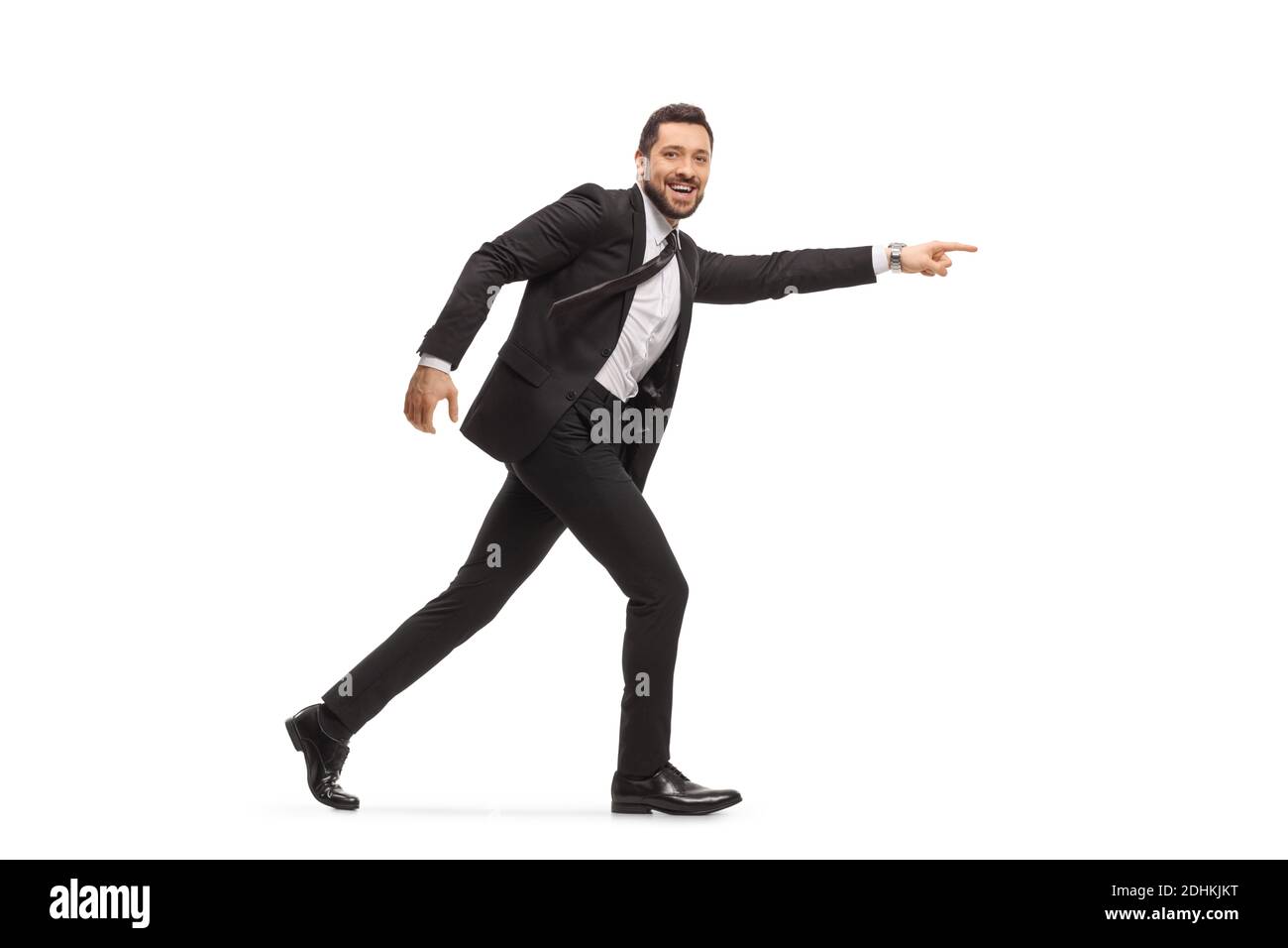 Sorridente bell'uomo in un vestito nero che corre e punta isolato su sfondo bianco Foto Stock