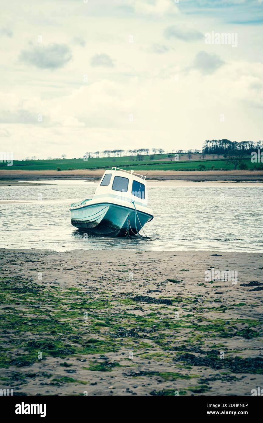 Una piccola barca a mezza cabina in un estuario con bassa marea ad  Alnmouth, Northumberland, Regno Unito Foto stock - Alamy