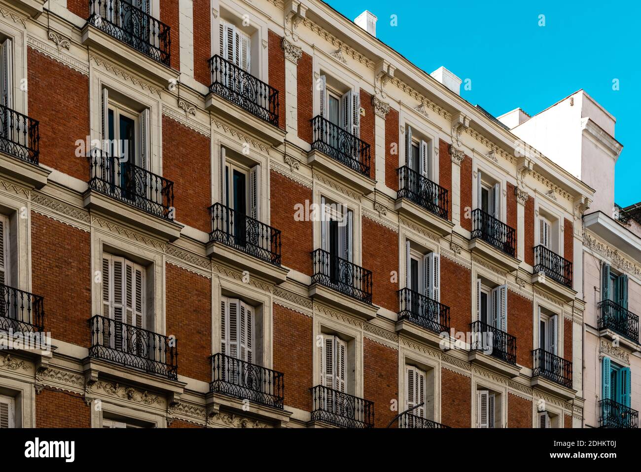 Vecchio edificio residenziale con facciata in mattoni e balconi in ferro a Madrid. Controllo degli affitti e concetto immobiliare Foto Stock