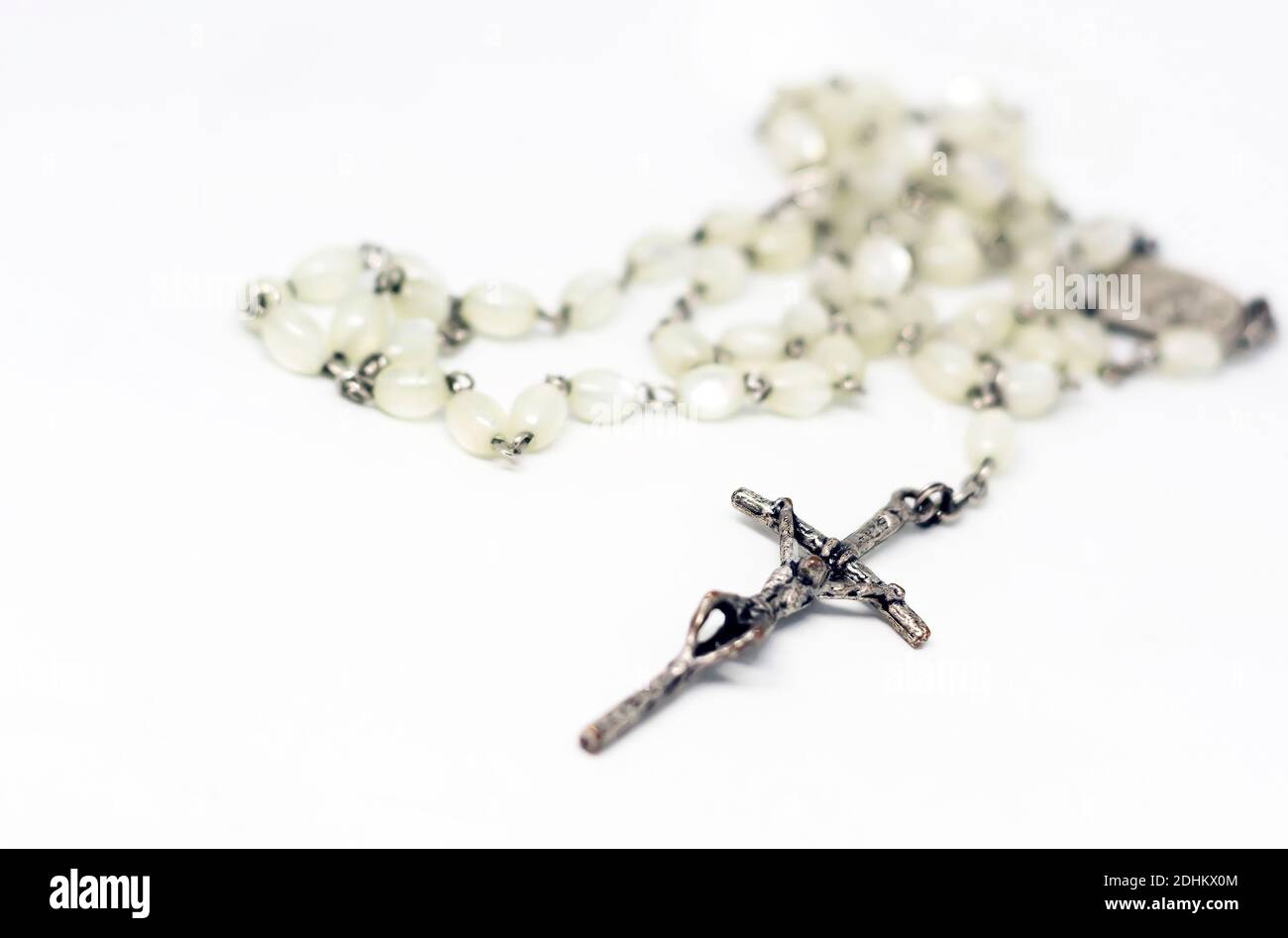 Rosario in madreperla bianca con crocifisso in argento isolato su sfondo bianco. Preghiera e devozione. Oggetto religioso. Foto Stock