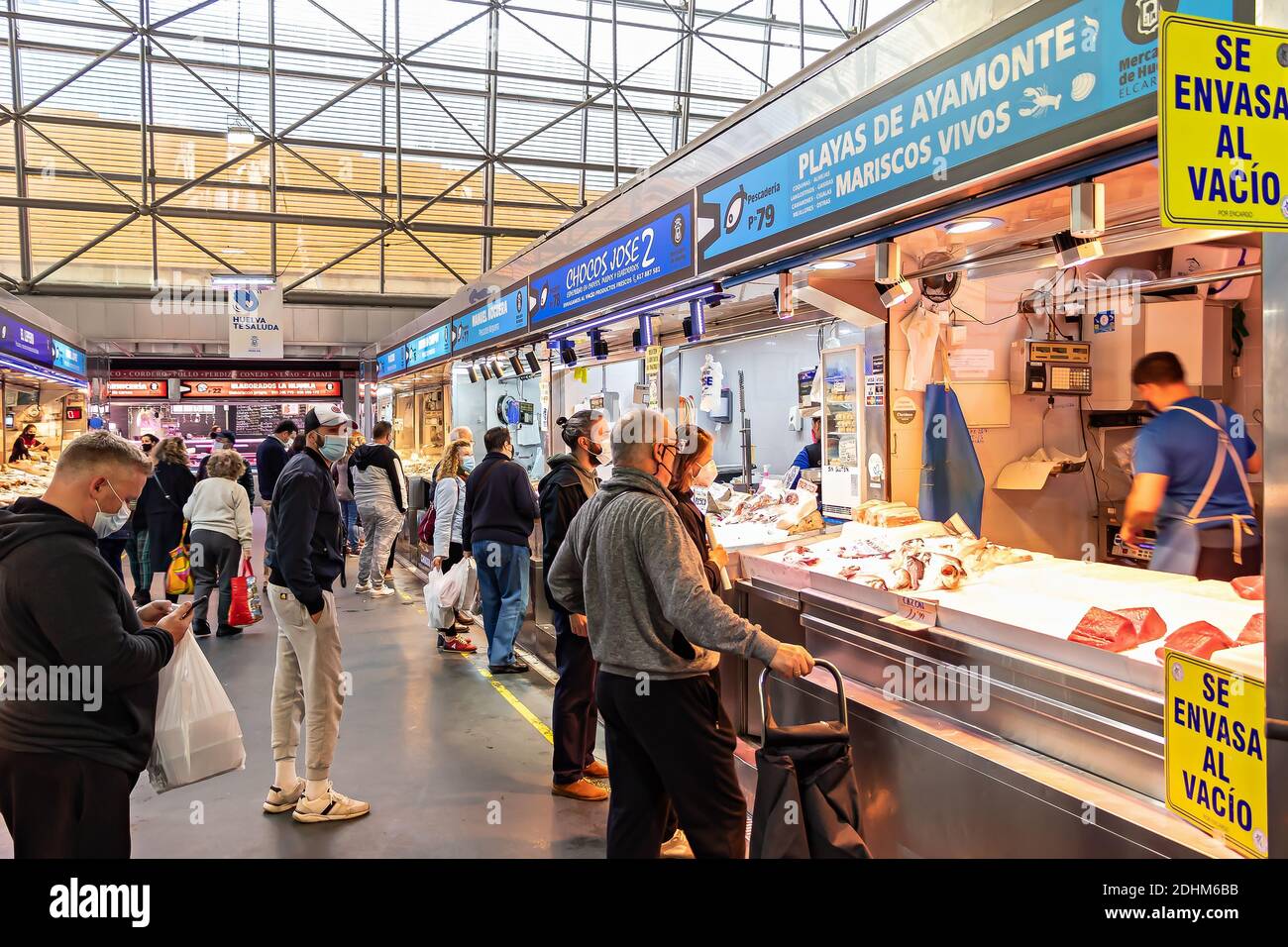 Huelva, Spagna - 11 dicembre 2020: All'interno del mercato Mercado del Carmen. Persone che acquistano frutti di mare , indossare maschera protettiva viso due COVID-19 Coronavirus Foto Stock