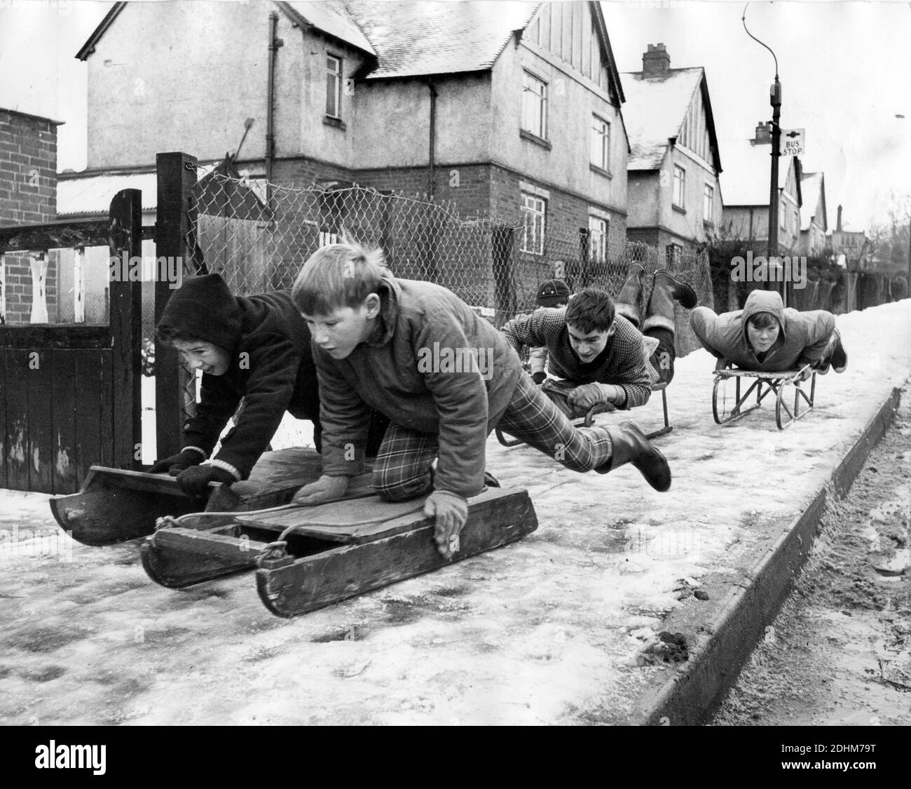 Ragazzi bambini che slittano sul marciapiede Bridgnorth Shropshire Gran Bretagna UK 1964 inverno 1960 bambini su slitte slitta Foto Stock