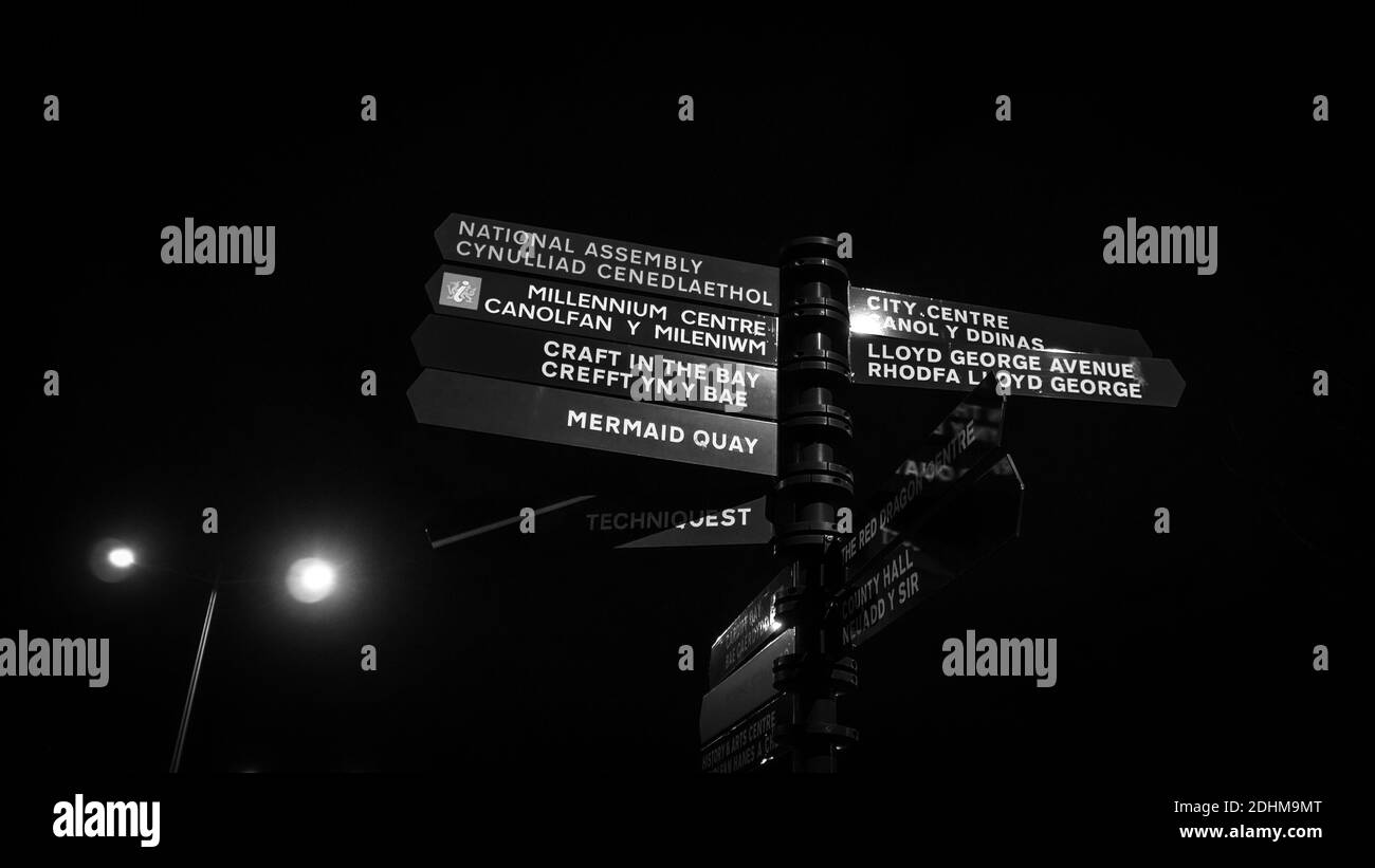 Indicazioni stradali per Mermaid Quay a Cardiff, Galles di notte in bianco e nero Foto Stock