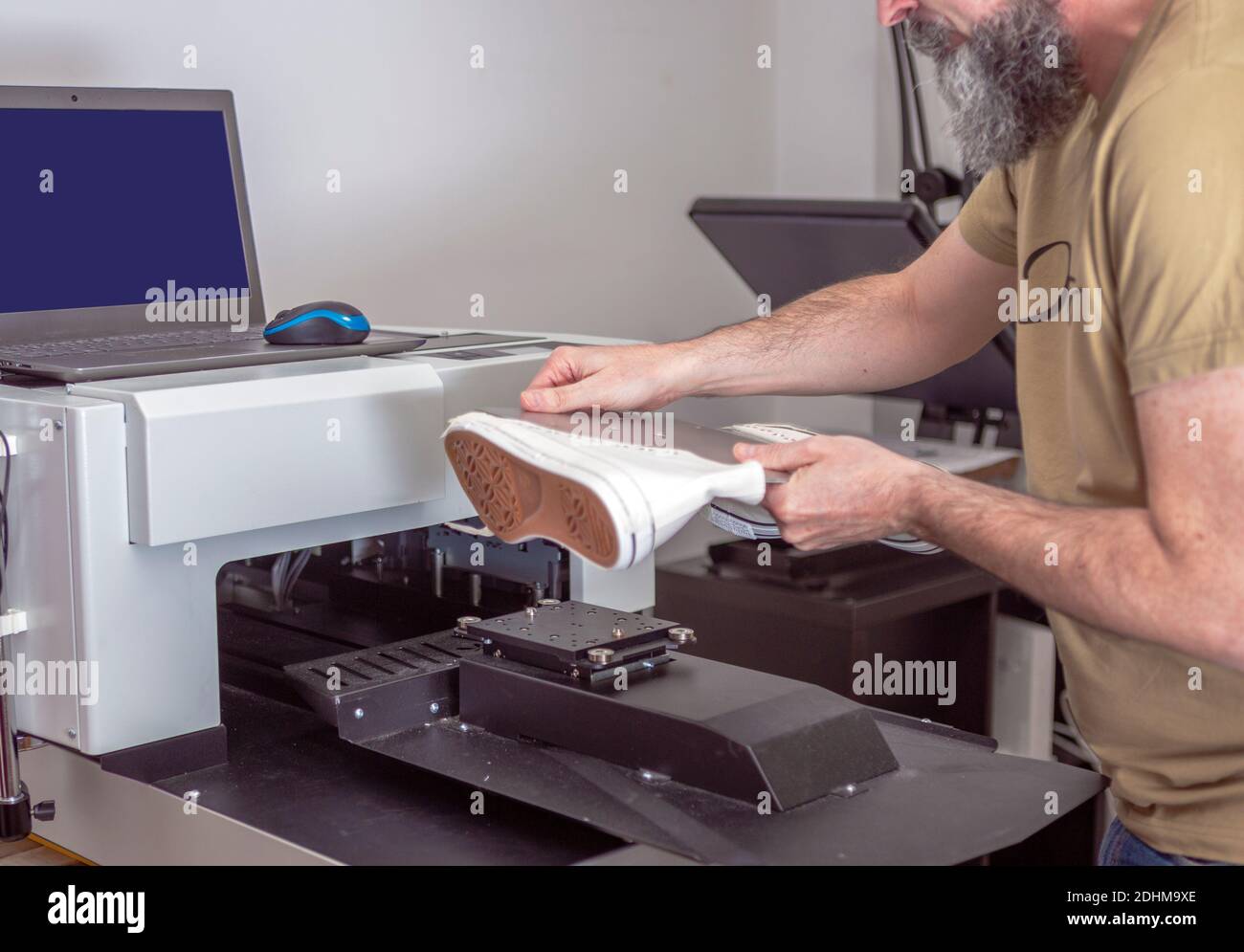 macchina operatrice di stampanti tessili uomo-lavoro per la personalizzazione nello sport scarpe Foto Stock