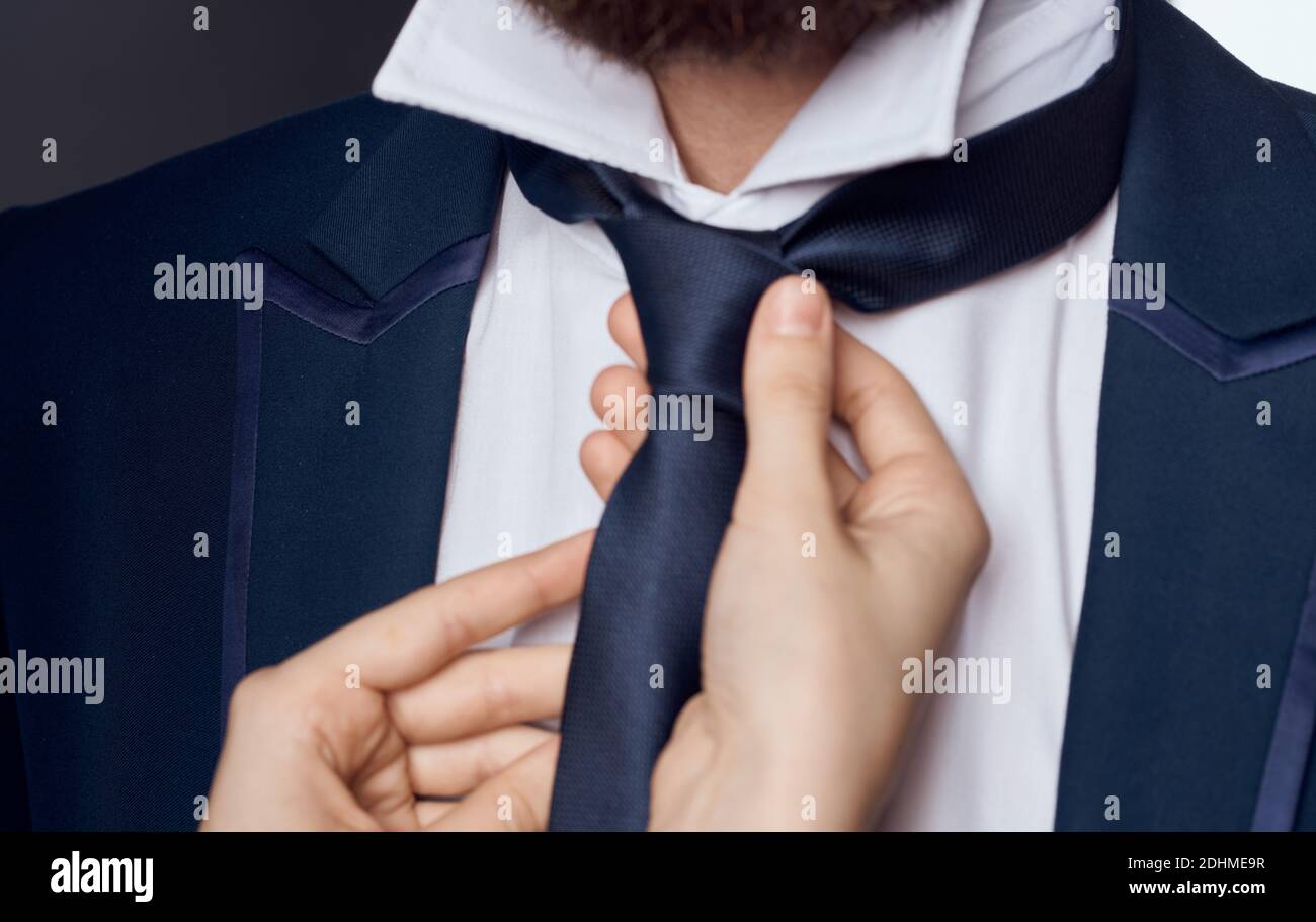 Le mani delle donne si legano intorno al collo della classica tuta maschile barba modello Foto Stock