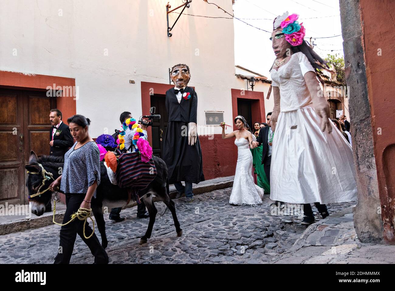 Un asino decorato conduce la strada come burattini giganti chiamati mojigangas danza durante una festa di nozze parando attraverso le strade San Miguel de Allende, Guanajuato, Messico. Foto Stock