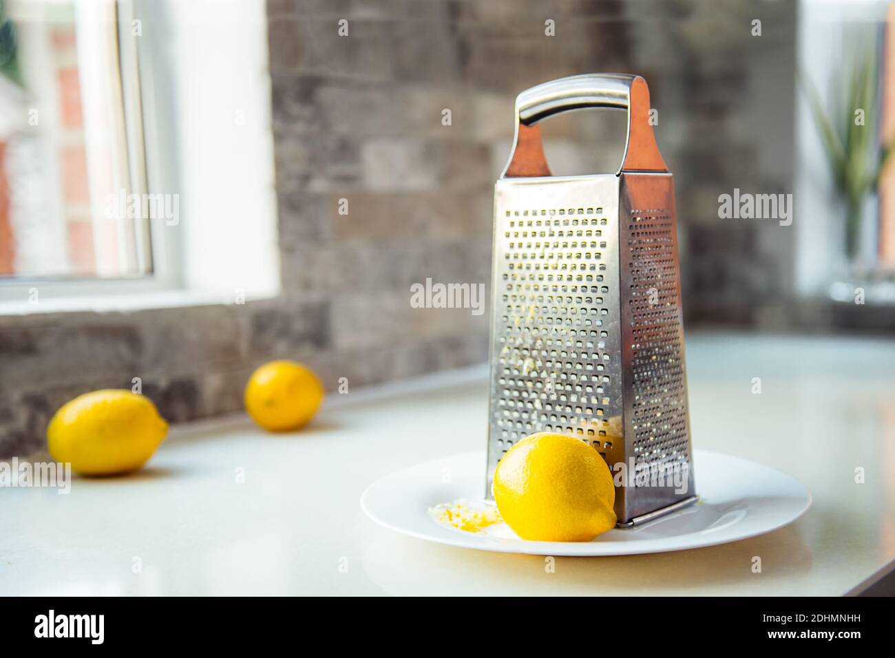 Scorza di limone e limone con grattugia di metallo sul piatto bianco in  piedi sul tavolo da cucina. Giallo e grigio colori trendy dell'anno 2021.  Selettivo Foto stock - Alamy