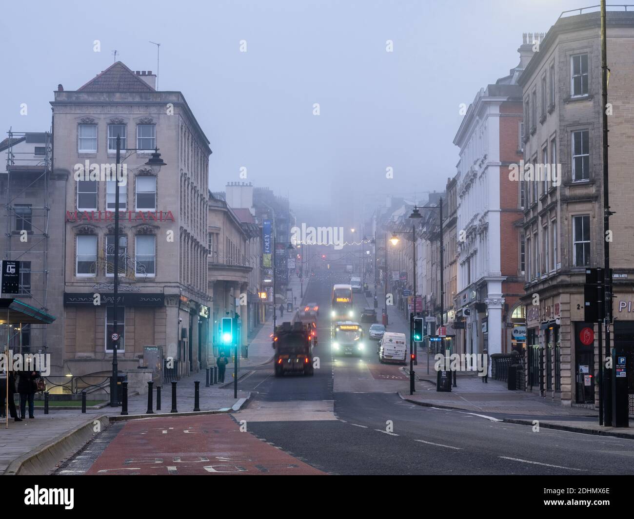 Il traffico scorre sulla ripida collina di Park Street a Bristol, dove il caratteristico Wills Memorial Building è avvolto dalla nebbia invernale. Foto Stock