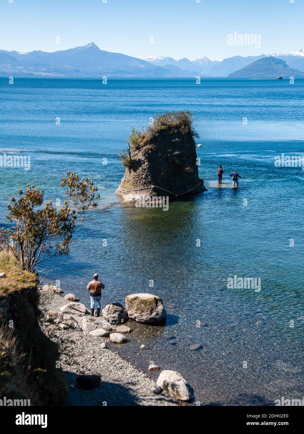 Osorno, Cile - 27 settembre 2009: Due uomini stanno pescando nel lago Rupanco, con le montagne vulcaniche delle Ande Patagoni alle spalle. Foto Stock