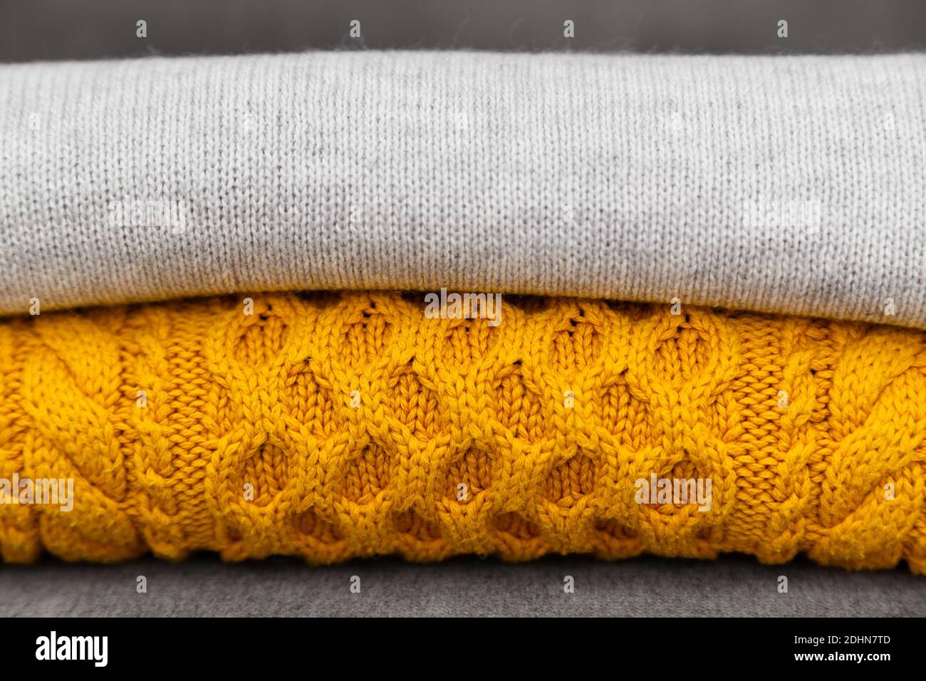 I pullover lavorati a maglia si avvicinano ai colori grigio e giallo alla moda. Colori dell'anno 2021. Una pila di comode pullover a maglia, concetto caldo Foto Stock