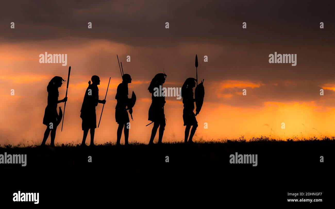 Guerrieri Maasai contro il sole che tramonta. Maasai Mara, Kenya. Foto Stock