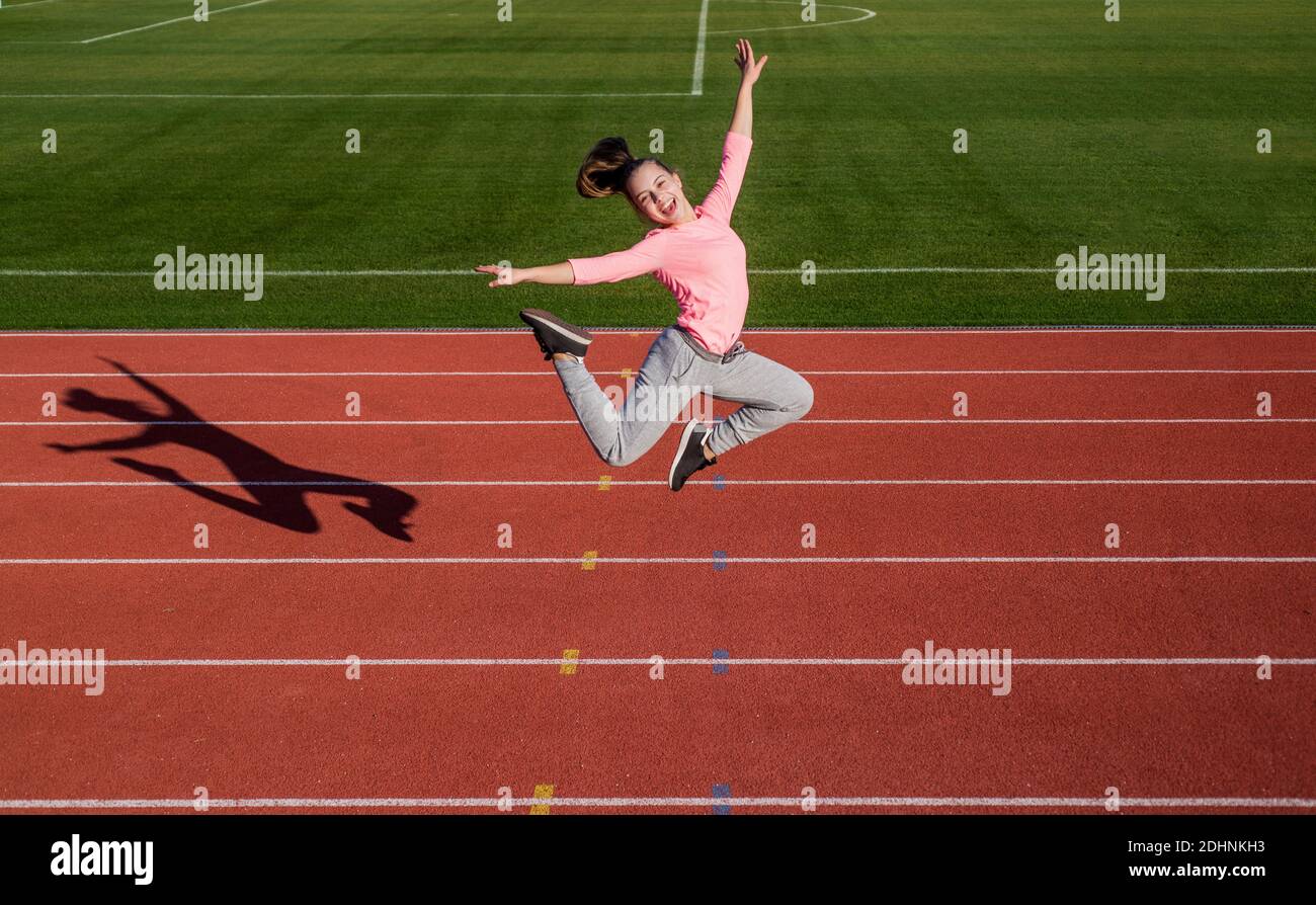 Energia dentro di lei. Piena di energia. Allenamento all'aria aperta. Sicuro e libero. Ragazza teen che salta sullo stadio. Bambino in abbigliamento sportivo. Bambino fare esercizio su pista da corsa. Infanzia sana. Foto Stock