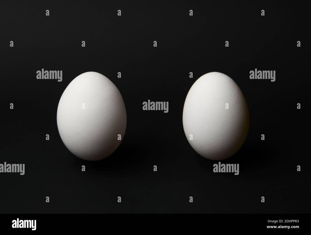 Due uova bianche su sfondo nero. Uova di pollo su sfondo nero con spazio per il testo Foto Stock