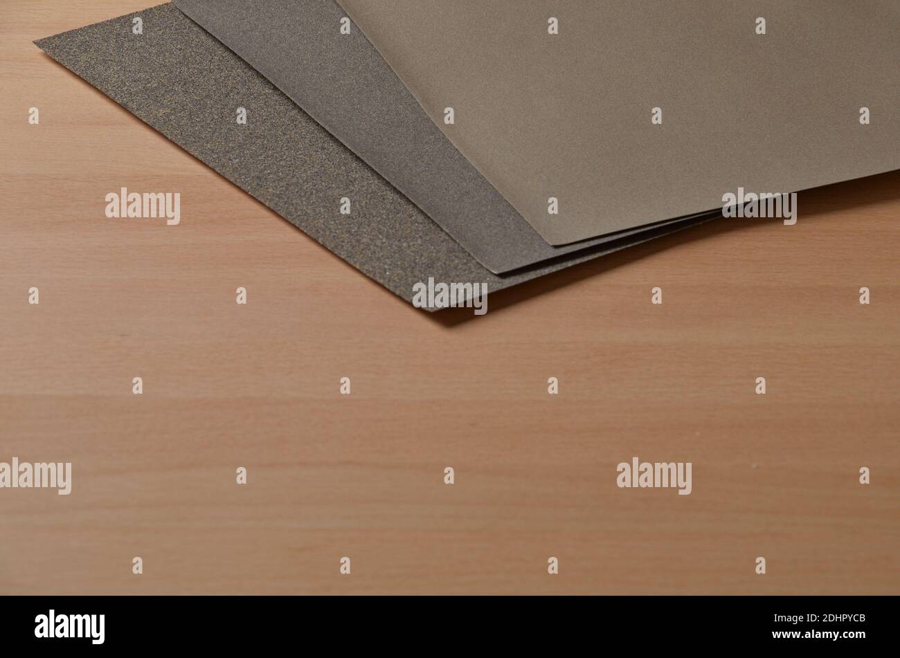Carta vetrata marrone resistente all'acqua su un tavolo di legno leggero in faggio. Carta vetrata su banco di lavoro in legno leggero di faggio. Foto Stock