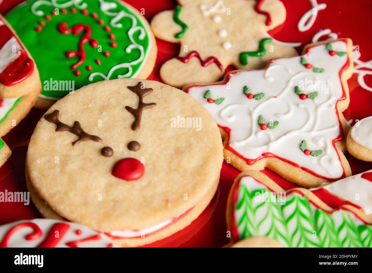 Piatto rosso pieno di biscotti natalizi colorati - Natale le ricette della vigilia - le tradizioni culinarie di festa di Natale Foto Stock