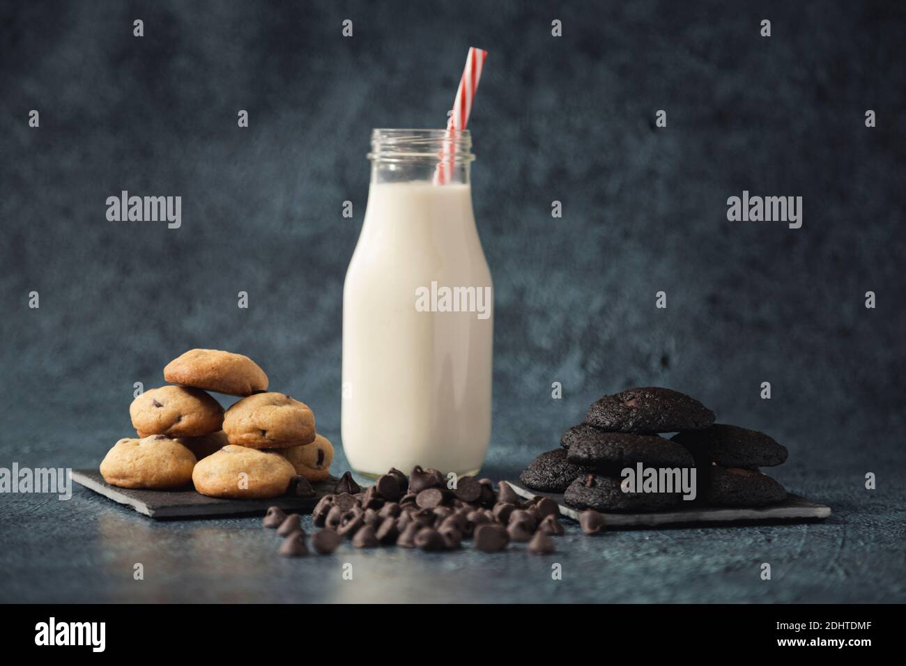 Mini biscotti al cioccolato serviti su un elegante piatto nero con un bicchiere di latte - spuntini gourmet Foto Stock