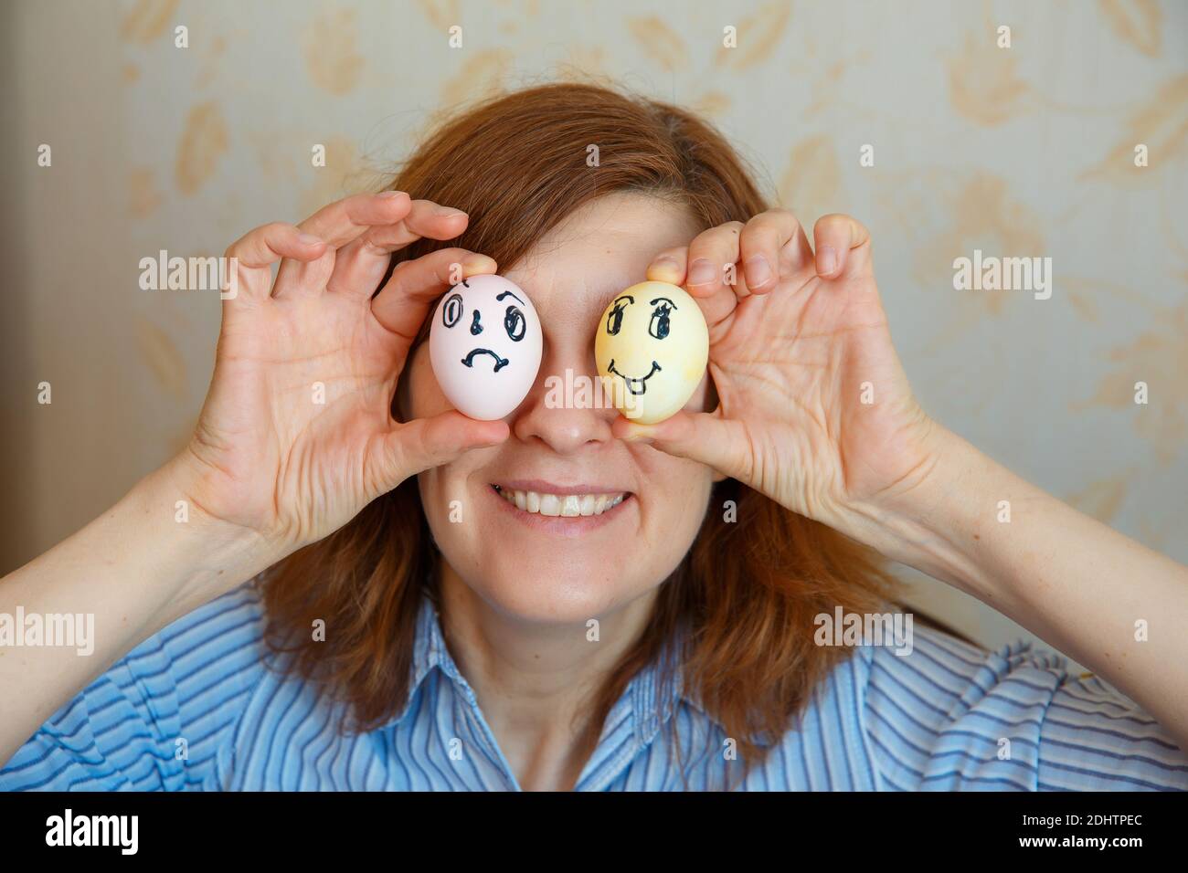 Ragazza mostra uova dipinte per Pasqua con volti divertenti. Buona pasqua Foto Stock