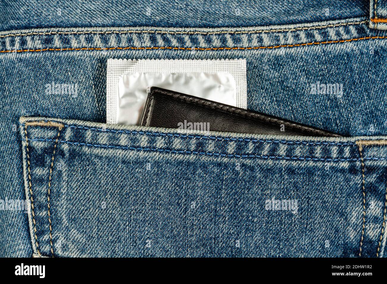 un preservativo in una confezione d'argento e un portafoglio che si attacca da una tasca per i jeans Foto Stock