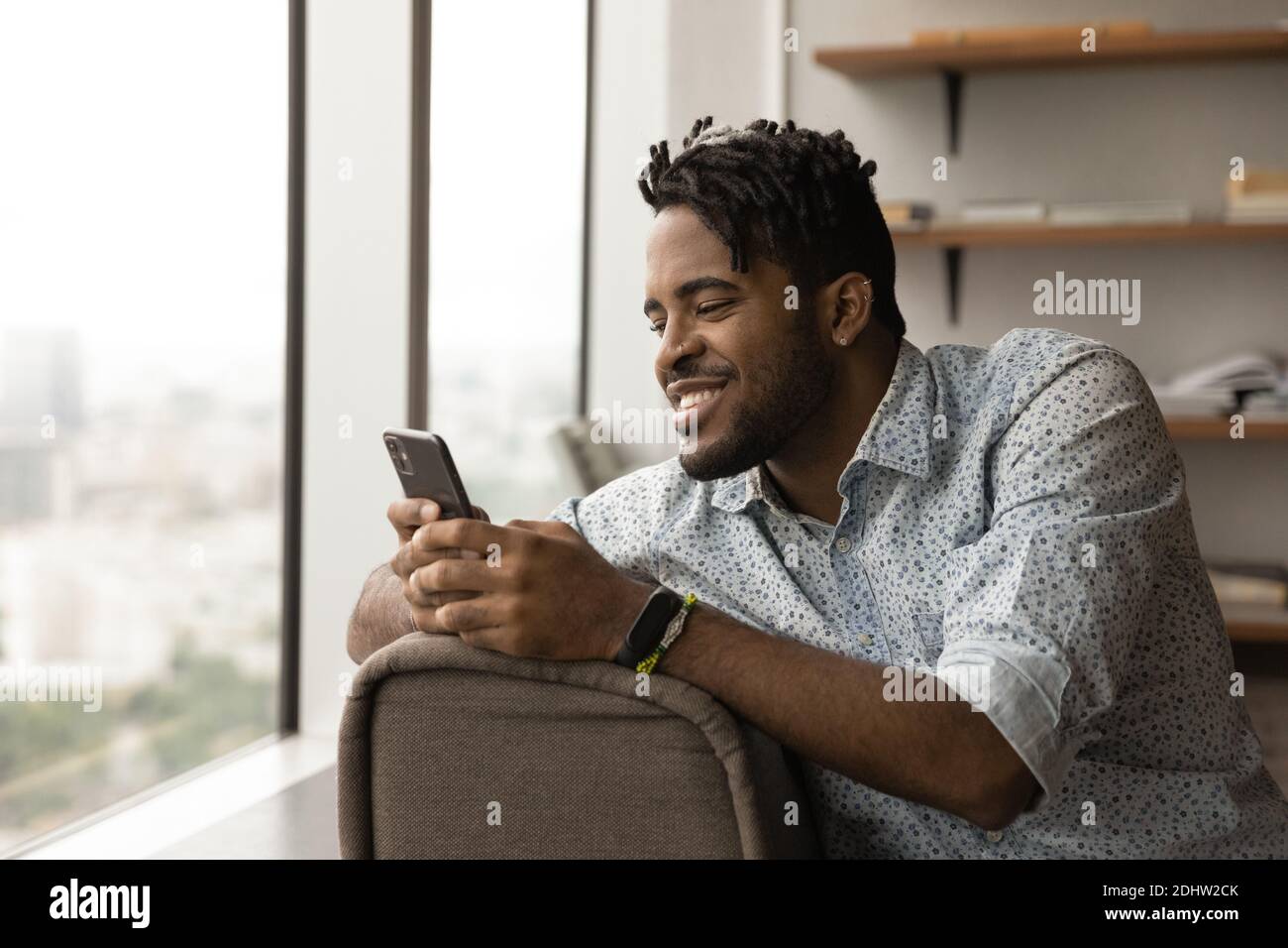 Sorridente afroamericano uomo usare cellulare testing Foto Stock