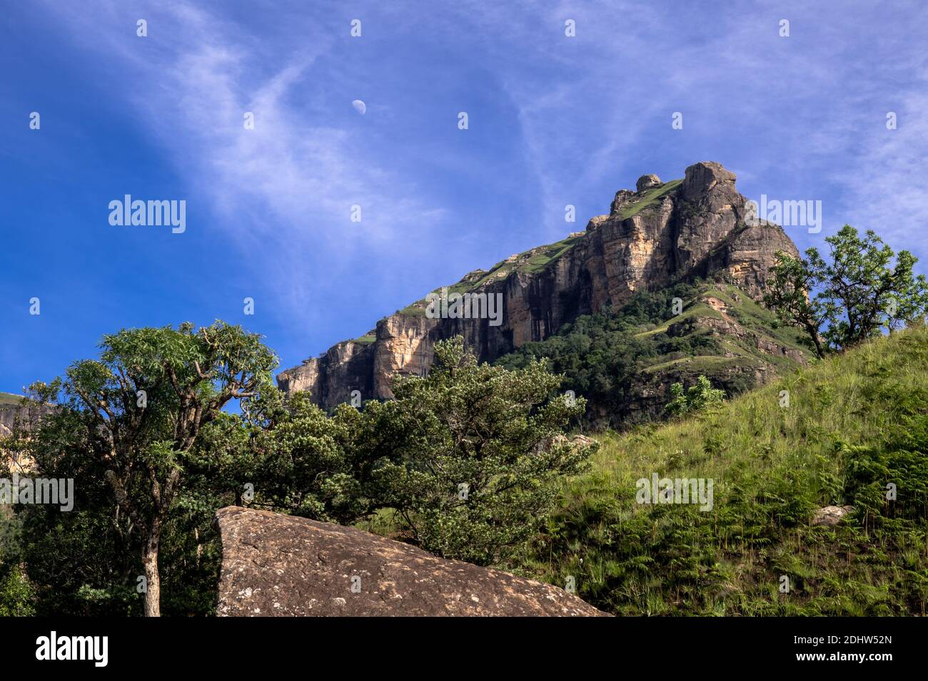 Montagna che si aggetta su una collina rocciosa contro il cielo blu e il verde a Drakensburg, Sud Africa Foto Stock