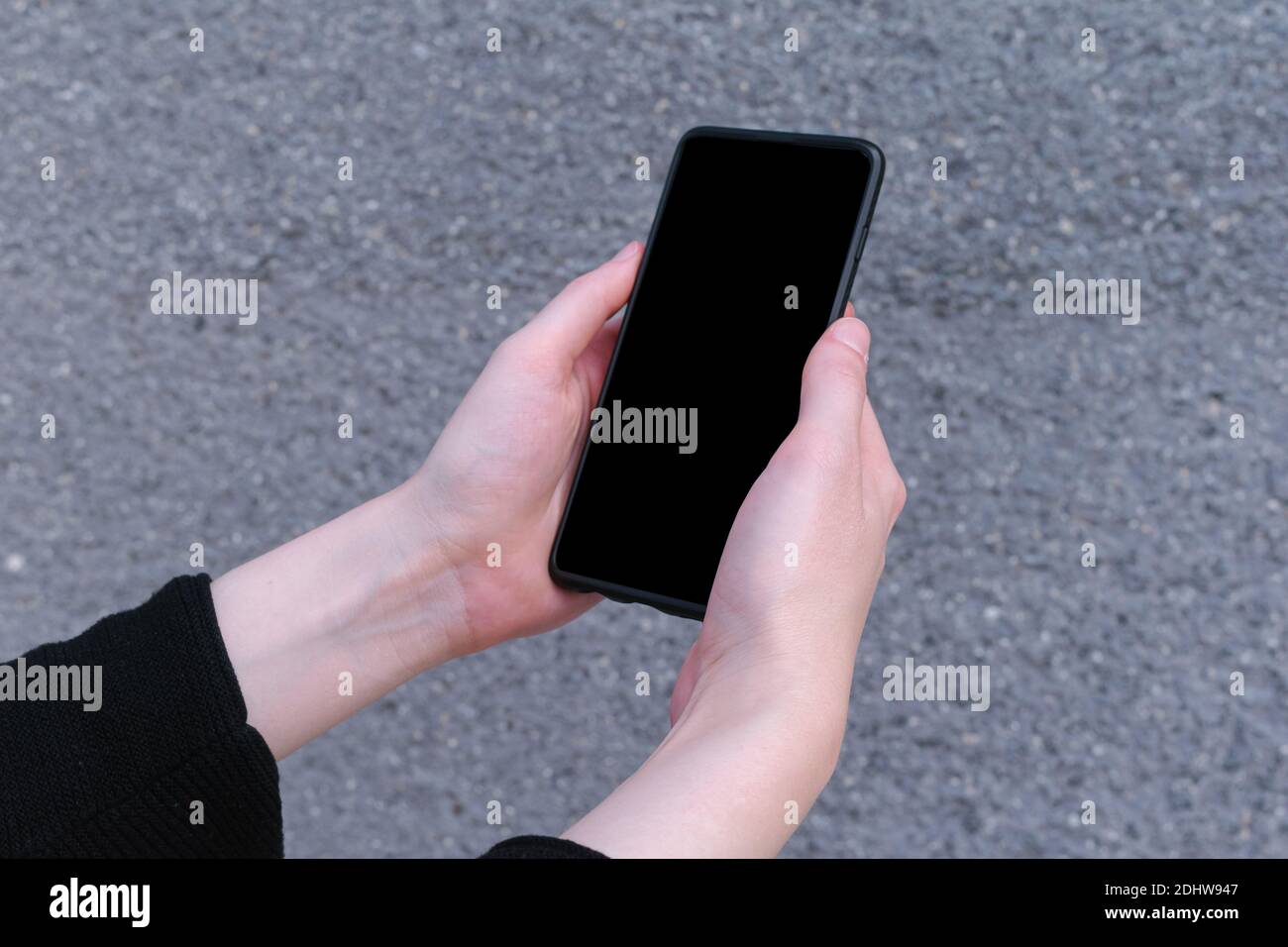 Smartphone da donna che tiene la mano con schermo nero vuoto mock up su sfondo grigio, business Foto Stock